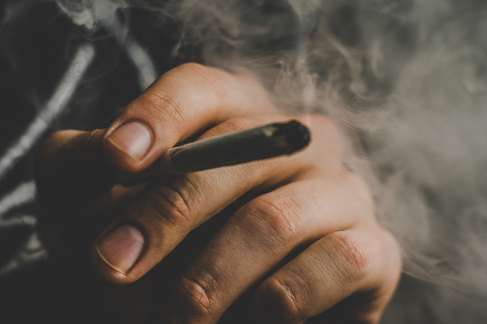 Close-up of man's hands smoking a lit joint